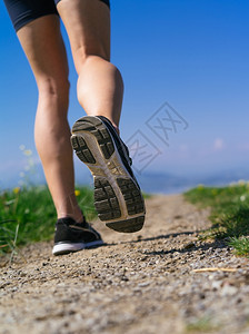跑步训练小路照片中一位年轻女子的腿和鞋她跑在国道A的碎石路上图片