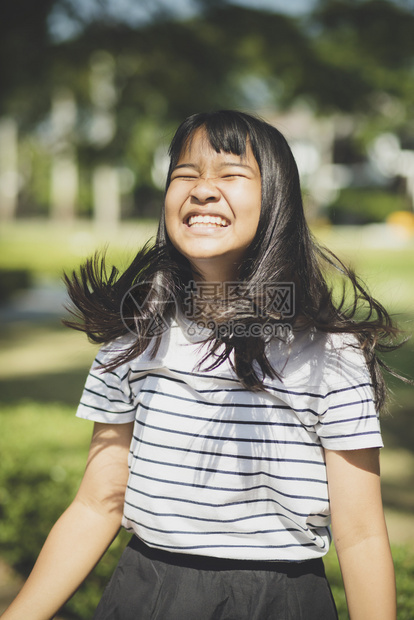 户外经过玩年轻亚裔青少的笑脸展示了风吹动的前额发毛图片