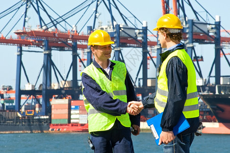 软垫两艘码头轮船在工业港口前握手卸下起重机和一艘集装箱货船码头工人微笑图片