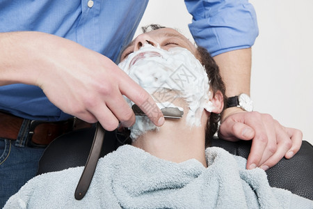 刮胡子男人眼睛披着毛巾的男子被理发师剃去涂满彩色背景图片