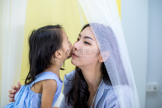 人们微笑成快乐的亚洲小女孩在家中亲吻她妈图片