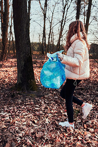 孩子清理森林的年轻女子志愿者将塑料垃圾装入袋子塑料污染和过多垃圾的概念环境问题损害对的责任真实人情况为了女士图片