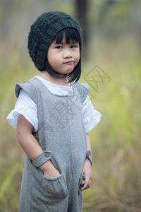 眼睛模型裙子身着羊毛兜帽的亚裔儿童在绿色公园站立的肖像照片图片