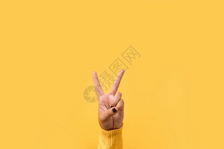 明亮的在黄色背景之上的胜利或和平标志手势五表示胜利或和平标志黄色的艺术图片