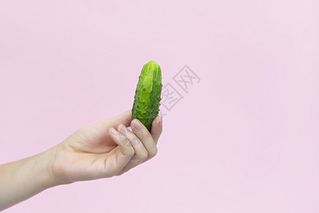 干净的自然粉色女手握明绿黄瓜在粉红的班纳与世隔绝复制空间蔬菜女手握亮绿黄瓜粉红色与世隔绝背景图片
