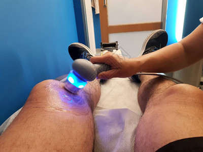 关心腿物理治疗师正在对膝盖受伤时使用超声波头感应器进行超声波疗法并采用超声波头感应器运动模糊健康图片