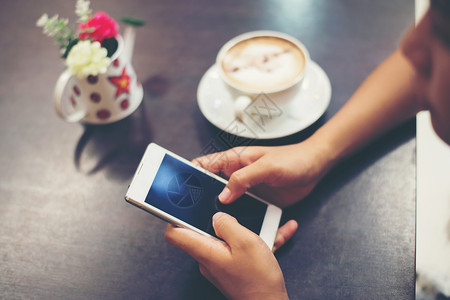 年轻的酒吧聪明女人在咖啡店用手机发短信的特写镜头女人在咖啡店用手机发短信的特写图片
