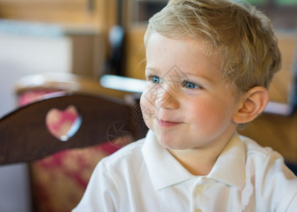 肖像孩子快乐的婴儿男孩18个月坐在饭桌椅上自然光照亮餐厅图片