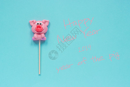 粉色的猪有趣的粉红猪棒糖和英文本新年快乐蓝色背景的猪年顶视图概念贺卡猪年棒糖和文本新年快乐的明信片最佳背景