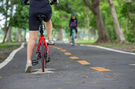 娱乐在亚洲女自行车手的背后戴着套的放在自行车女手的把上种族骑自行车图片