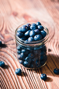 分散将新鲜的蓝莓放入罐子中一些水果在旧木制桌上自由散落食物收成图片