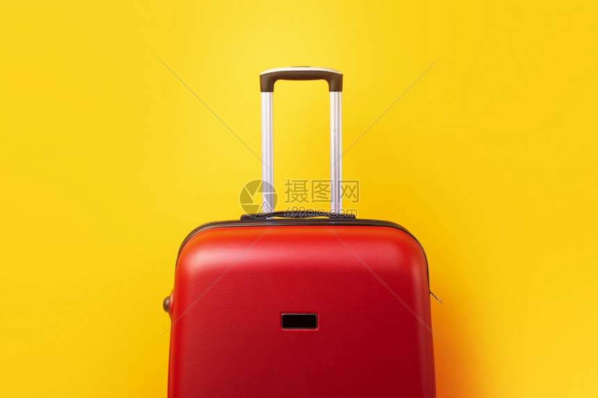 航程红色的旅行李箱在黄色背景上关闭的图片
