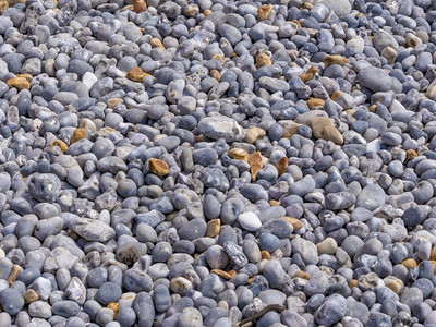 圆润的沿海自然沙滩上不同颜色和大小的平滑卵石背景图案图片