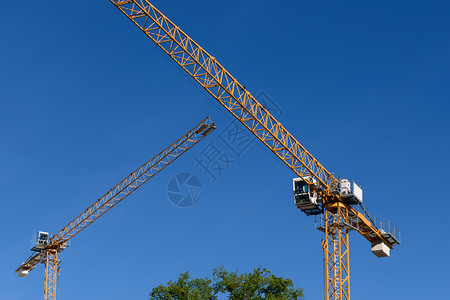 工作建筑学机械的两台蓝色天空背景的通用建筑起重机图片