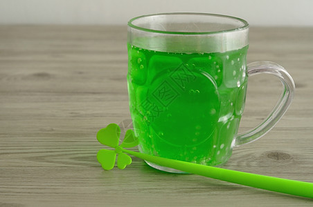 圣帕特里克日用4个叶木桩展示在啤酒杯中的绿色液体运气天四叶图片