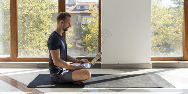 安全的自然抽象用笔记本电脑坐在瑜伽垫子上的全男图片