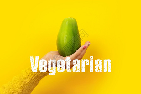 手黄色的绿木瓜在黄背景上水果加素食植物文摘时髦的图片
