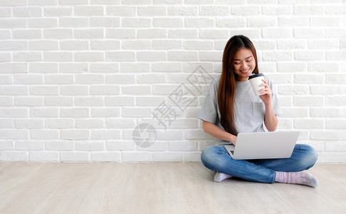 随意的现代网络年轻亚洲妇女使用笔记本电脑在白会议室背景中以临时形式举行咖啡杯并有复制空间人和技术生活方式等复制空间图片