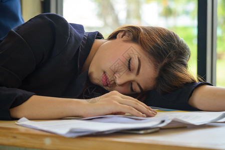 睡觉在办公室会议的年轻精疲力尽的亚洲妇女人们桌子图片