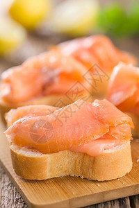 食物鱼片木板有选择焦点在木板上袋式面包纸抽炸鲑鱼切片图象巴格特上有烟熏鲑鱼的焦点三分之一早餐图片