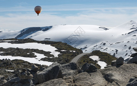 游客岩石在dalsnibba或63号公路上方的热气球通向北面Geirangerfjord高视线的63条旅游道路山顶夏季有雪峡湾背景图片