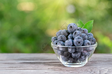 收成可口蓝莓在木板上用玻璃碗的叶子在木板上用玻璃碗的叶子来做白莓抗氧化剂图片