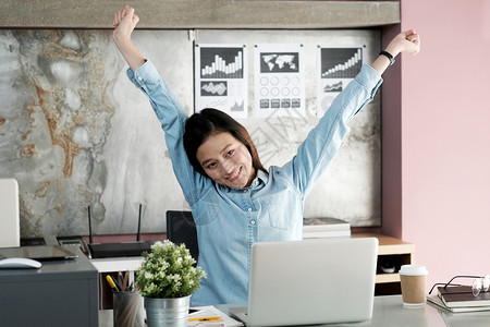 技术年轻的西安办公室女青年在桌上用笔记本电脑办公室生活方式商业状况等工作时伸展身体以放松力互联网尽管图片
