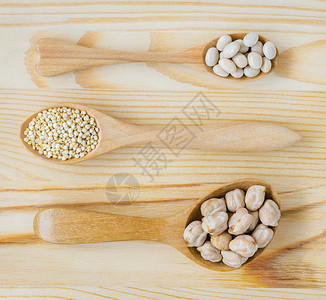 白豆quinoa种子和木勺中的鸡尾豆木桌上的顶端视图健康食品概念肾棕色的藜图片
