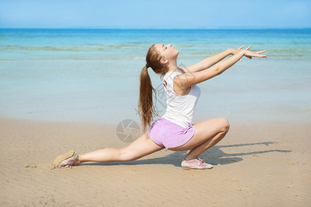 迷人的年轻女子在海滩上锻炼正做身体人们图片