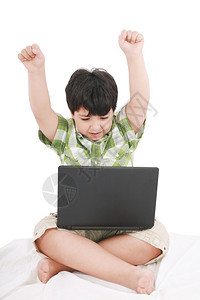 微笑可爱的用笔记本电脑在床上穿白衣服的小可爱男孩友谊图片