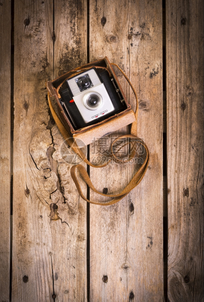 复古的一个古老的照相机在它原来的旧皮革箱子里用木制背景它的图片