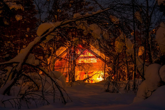 冰白色的山芬兰北部深厚的冬季森林和许多雪小型木屋和夜间照明在冬森林中点亮的木房图片