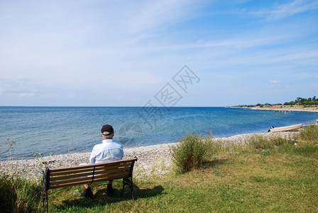 一个坐在沙滩旁观夏日的长椅上男人景观假期瑞典图片