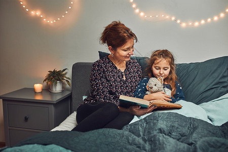 人们快乐的母亲妈睡前在床上给女儿看书睡前读故事给孩子听睡前故事图片