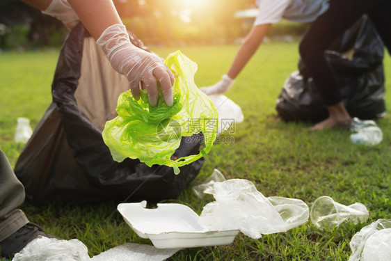2个人把垃圾塑料瓶装在黑袋里清晨的公园里老绿色黑图片