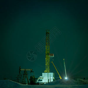 巴斯塔钻井机和油泵插孔的夜景晚气体图片