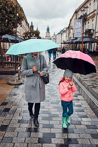 女士带着粉红和蓝雨伞的妈女儿在市区中走动雨季阴凉秋天下女人和小孩拿着雨伞在市区中走动雨季秋天下后部阴沉图片