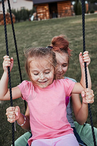 拥抱少女在后院的一家庭操场上与妹玩耍快乐笑的姐妹们在夏日一起秋千玩得开心真人情姐孩子图片