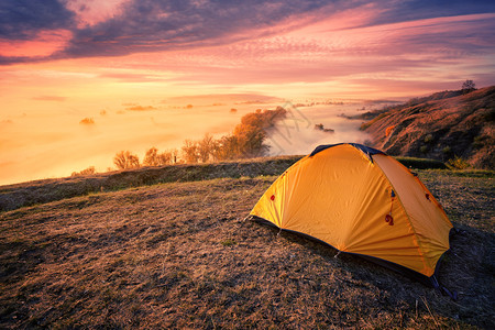 发光的在雾河上山顶一个丘上橙色旅游帐篷风云黄昏的天空旅行和隐私概念雾河上山头的橙色旅游帐篷野营戏剧图片