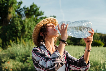 在稻田收获水时农民妇女从塑料瓶中饮用水农场人们渴图片素材