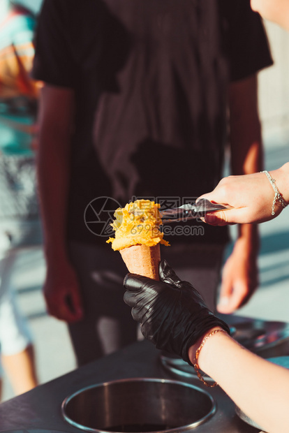 经过年轻的男孩在糖果店买冰淇淋一个街坊女人把勺黄色的冰淇淋一种图片