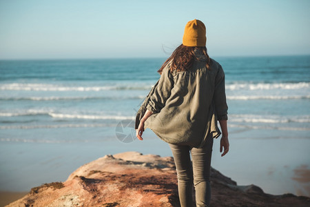 女人带着黄色的帽子走在悬崖上看海滩步行活动人们图片