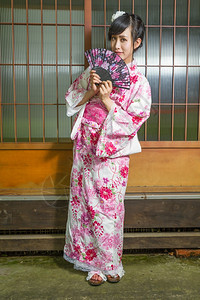 亚洲人浴衣裔妇女穿着和服在日本房子前的跟服保持图片