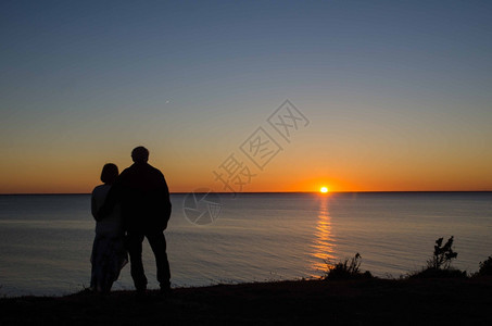 闲暇一对夫妇在海边的地平线看日落天空乐趣图片