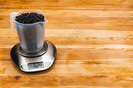 天然木质背景上不锈钢电子秤透明量杯中的干黑莓复制空间木质背景上电子秤量杯中的干黑莓带复制空间桌子烹饪自然图片
