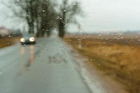 旅行挡风玻璃湿的雨滴在车上透过湿玻璃看下雨天透过湿玻璃看路雨滴在车上图片