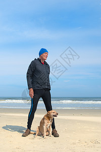 灰色的动物户外健康老人和狗在沙滩上跑腿图片