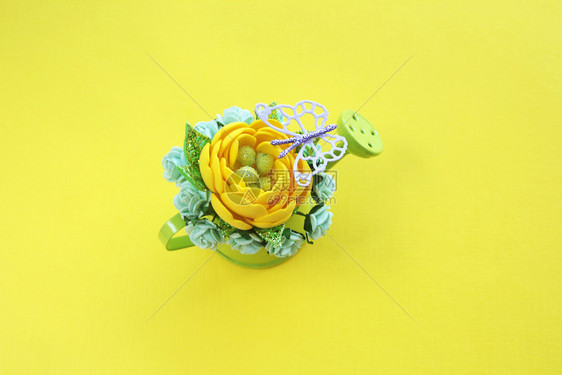 花的黄色手工造人花朵有闪光的叶子和许多绿色小水中的纸玫瑰在黄色背景和紫蝴蝶风下可使用小型绿水罐头植物群微型图片