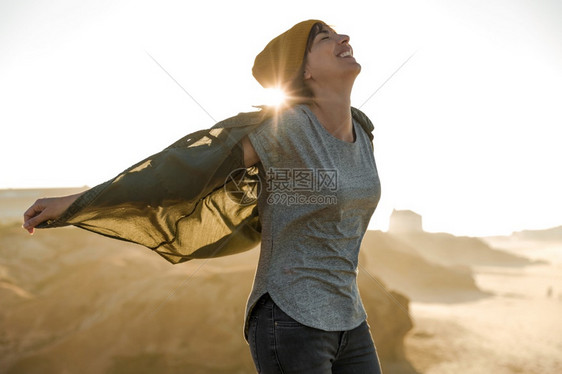 美丽的女人在海滩悬崖上戴着黄色的帽子徒步旅行者海洋远足图片