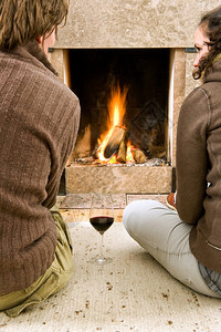 冬天一种地面年轻夫妇享受着温暖的火热用一杯酒喝图片